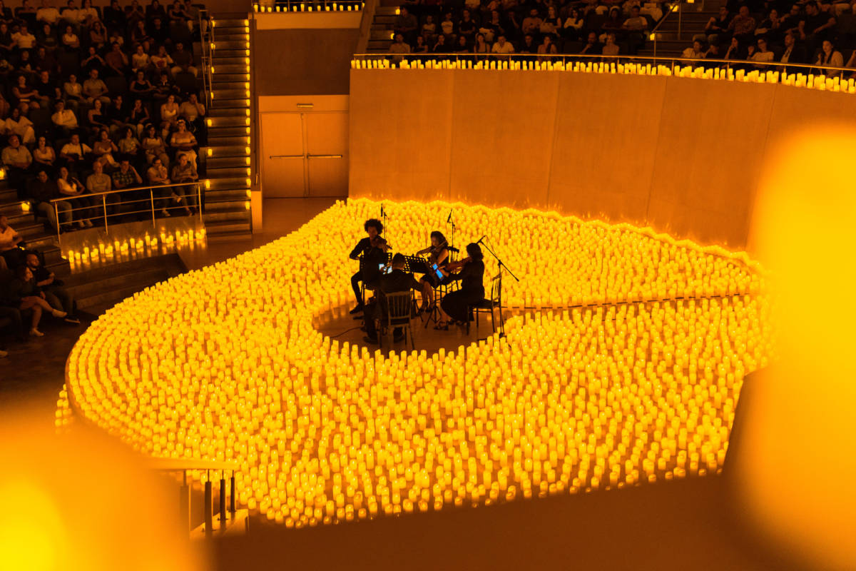 A string quartet performing amid a sea of candles