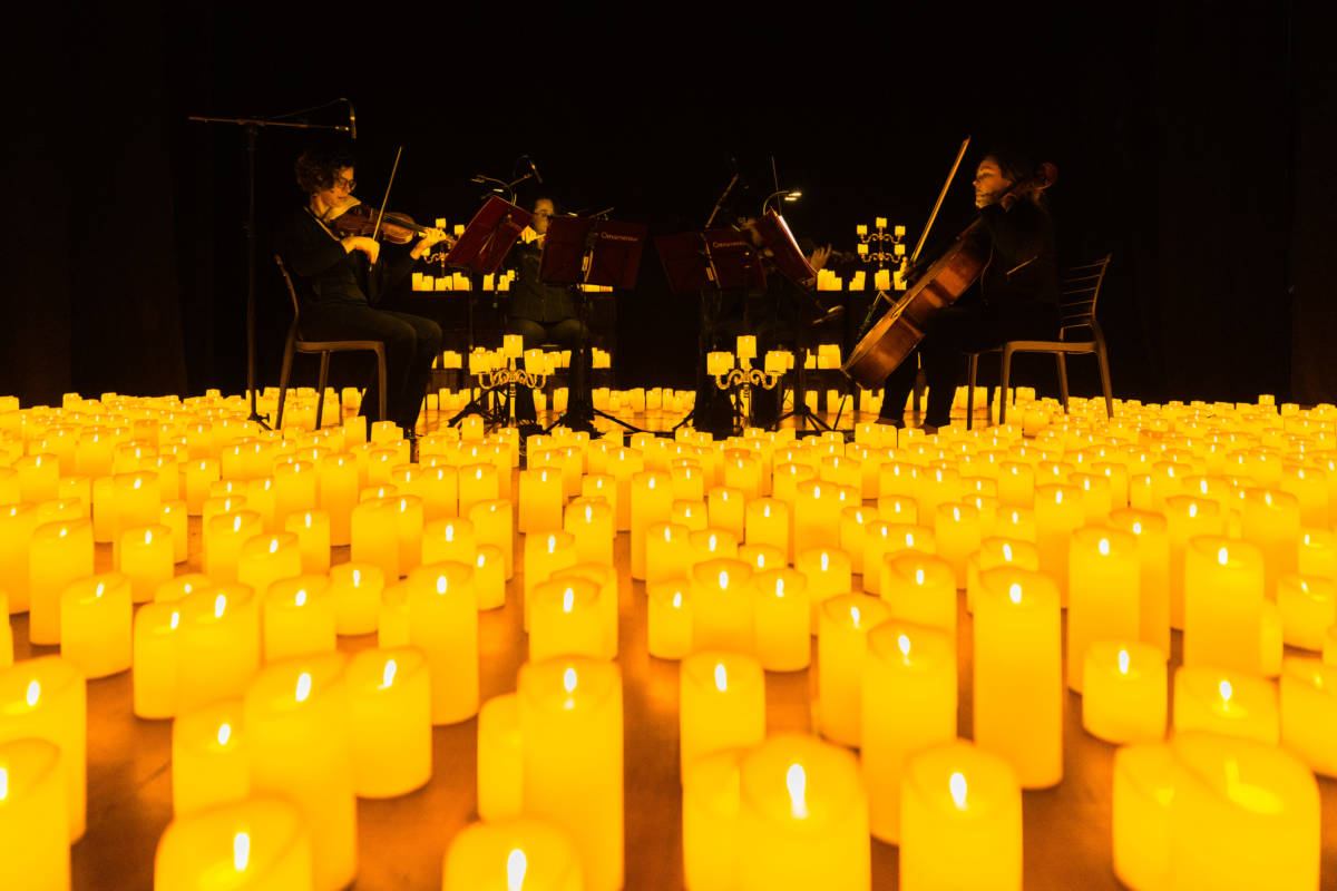 A string quartet performing amid a sea of candles