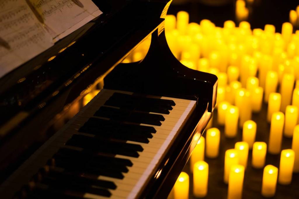 Close up of a grand piano surrounded by a sea of twinkling candles