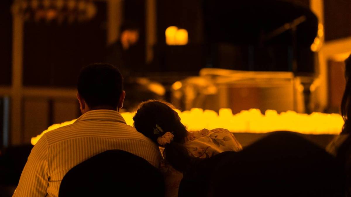 A woman resting her head on her friend's shoulder, as they both enjoy a Candlelight concert