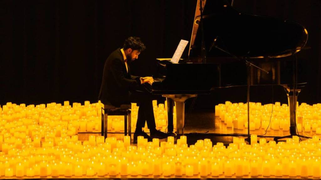A pianist performing amid a sea of candles