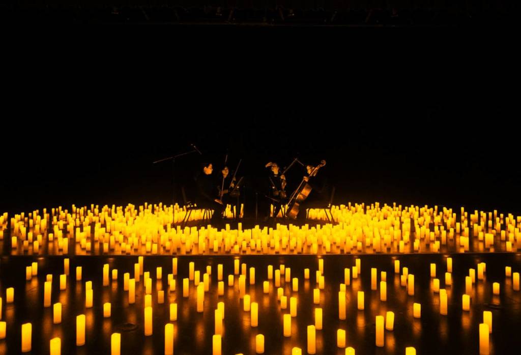 A string quartet performing amid a sea of candles