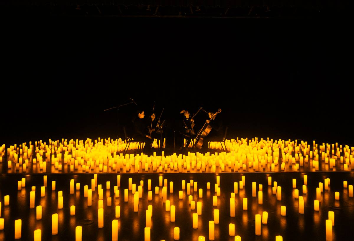 A string quartet performing amid a sea of candles