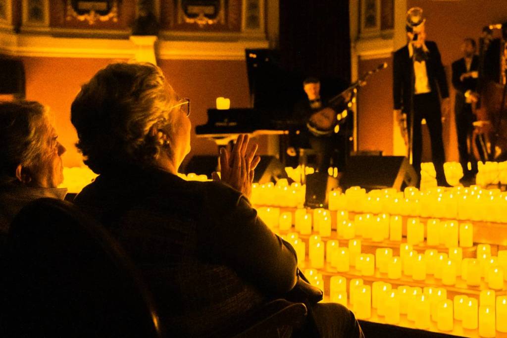 Audience members clapping and enjoying a Candlelight concert from the first row.