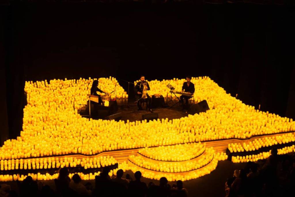 Un cuarteto de cuerda toca sobre un escenario cubierto de velas durante un concierto Candlelight.