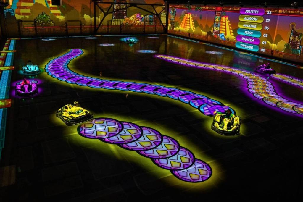 Weitwinkelaufnahme der BattleKart Arena in Fürth während des Spielmodus BattleSnake mit leuchtenden Projektionen auf dem Hallenboden