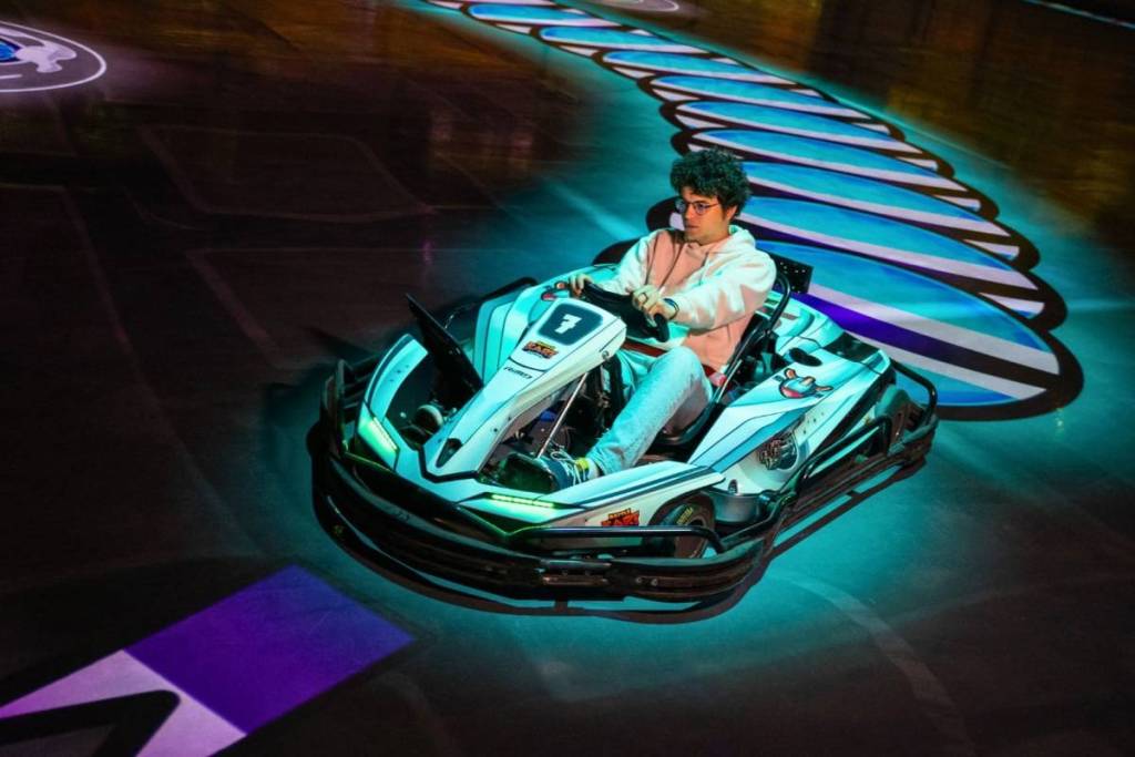 Konzentrierter Spieler in einem Elektro-Kart bei BattleKart Fürth steuert über die digital projizierte und interaktive Rennstrecke
