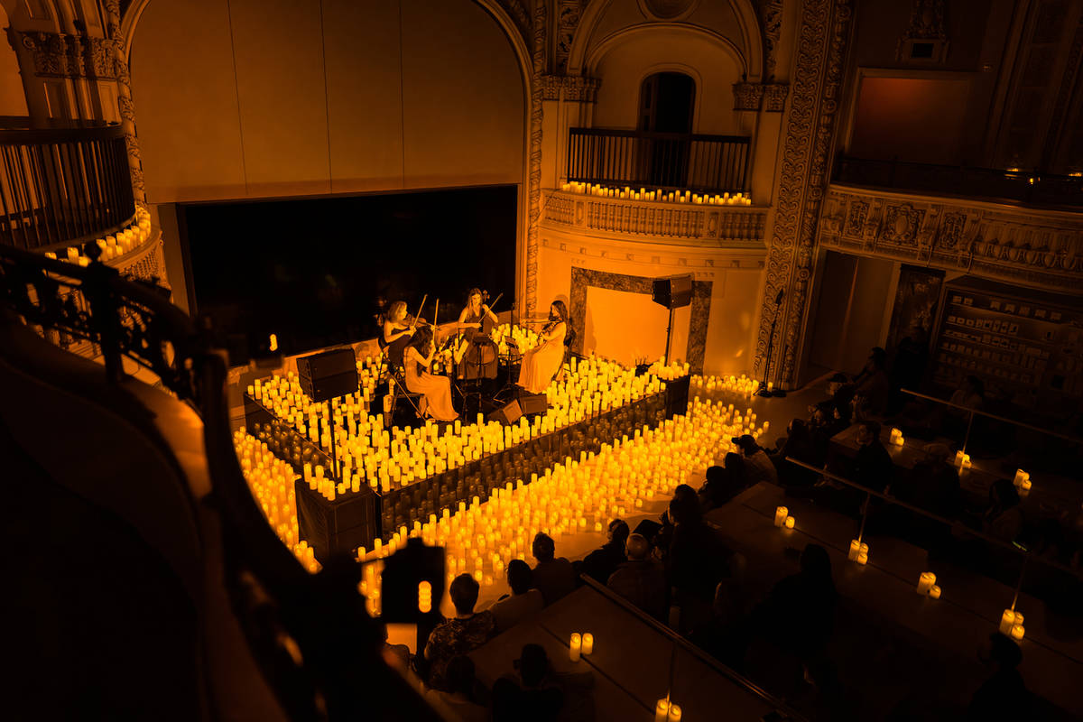 Cuarteto de cuerda tocando en un teatro iluminado por la luz de las velas