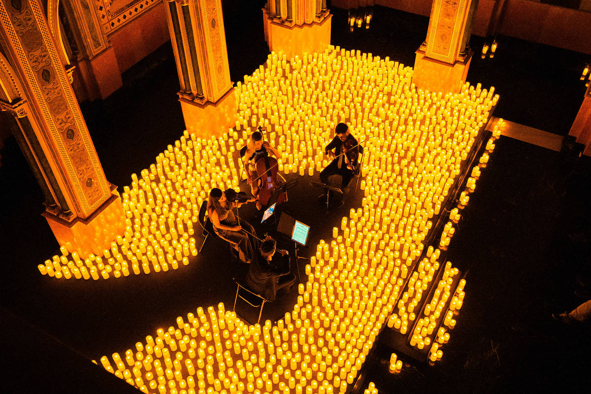 Plano desde arriba de un cuarteto de cuerda sobre un escenario cubierto de velas durante un concierto Candlelight.