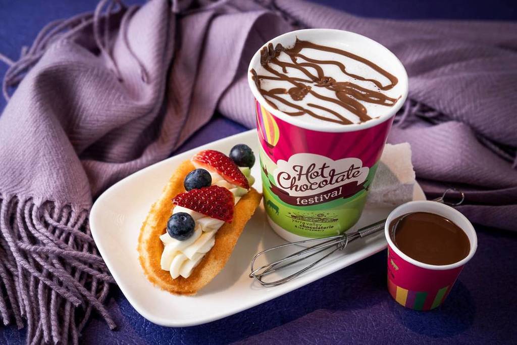 a hot chocolate with a sweet, berry-topped 'taco' next to it