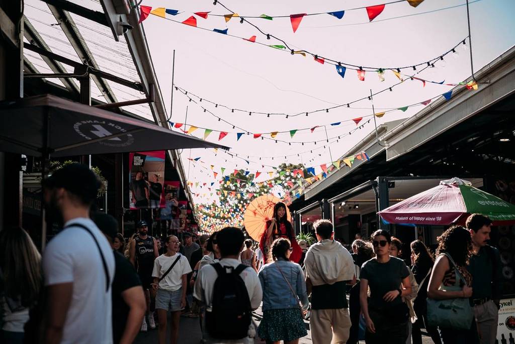 people walking down the laneway at Queen Victoria Market on a sunny summer day