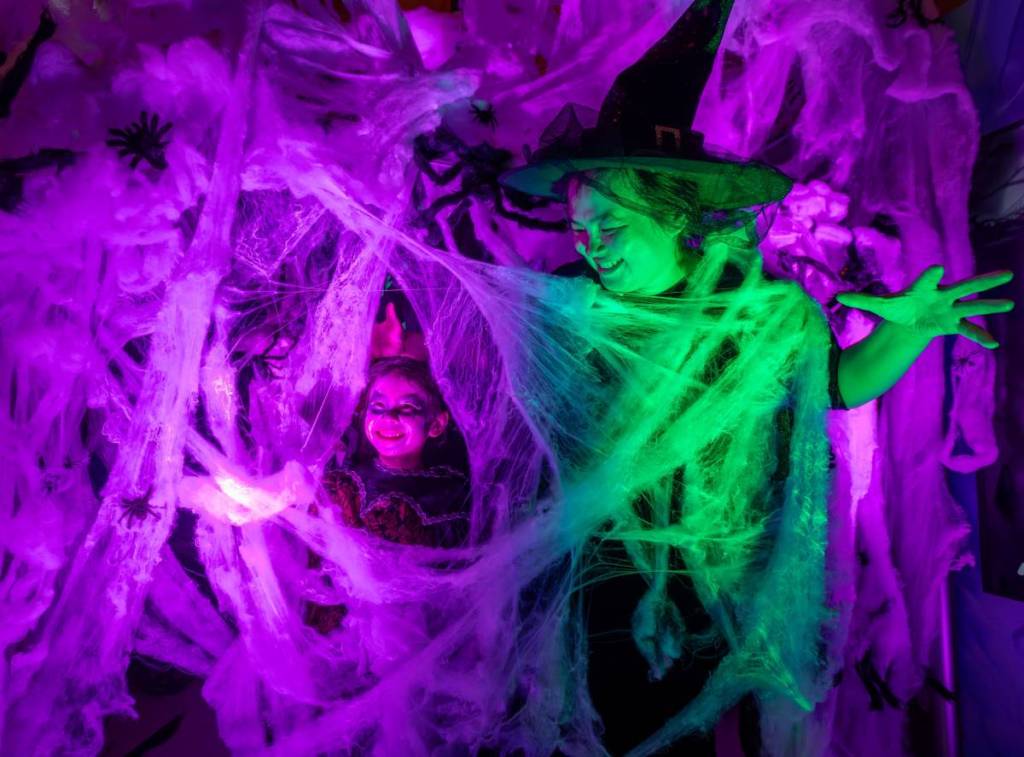children laughing in spider webs at Halloween at the Museum