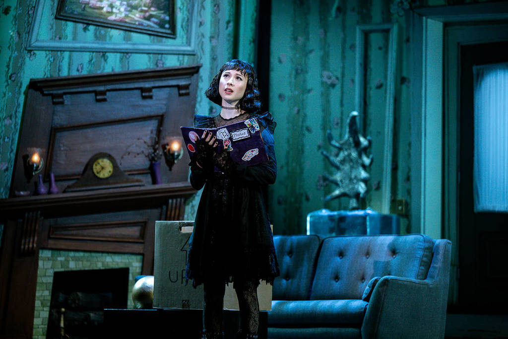 Lydia holding the book for the recently deceased in the Beetlejuice musical