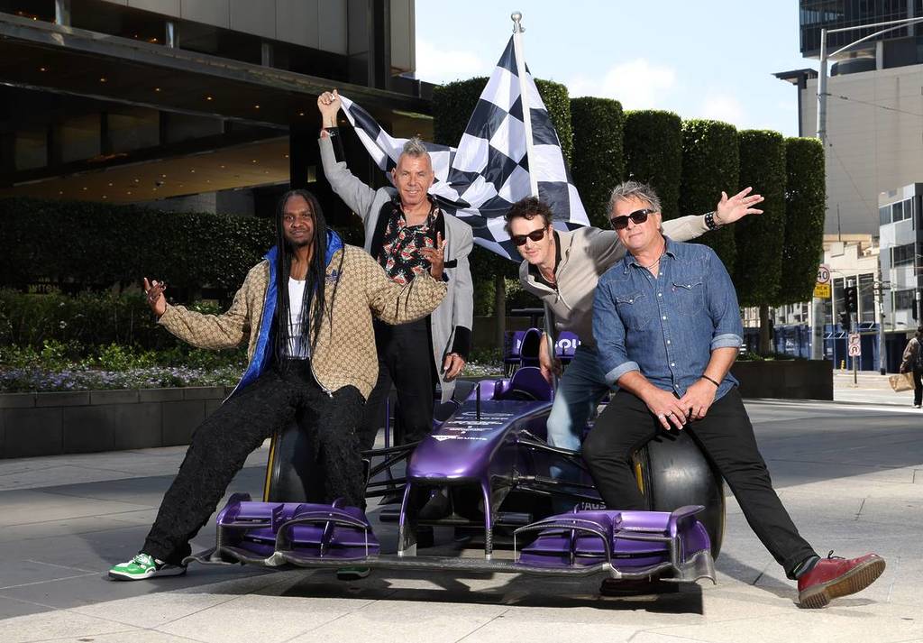 Baker Boy and The Living End posing with a small race car and a chequered flag