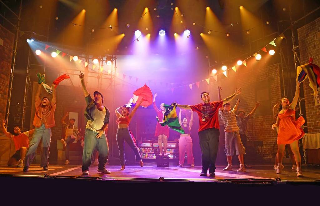 ensemble holding flags up at In The Heights