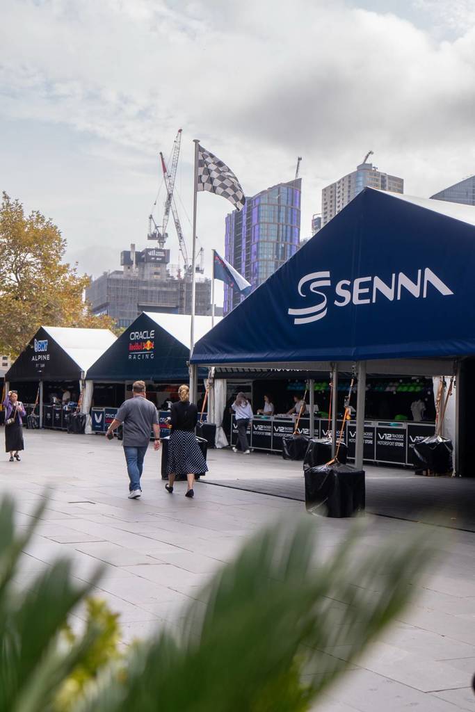 people strolling on the Riverwalk in front of Crown Melbourne with stalls set up for the Grand Prix celebration
