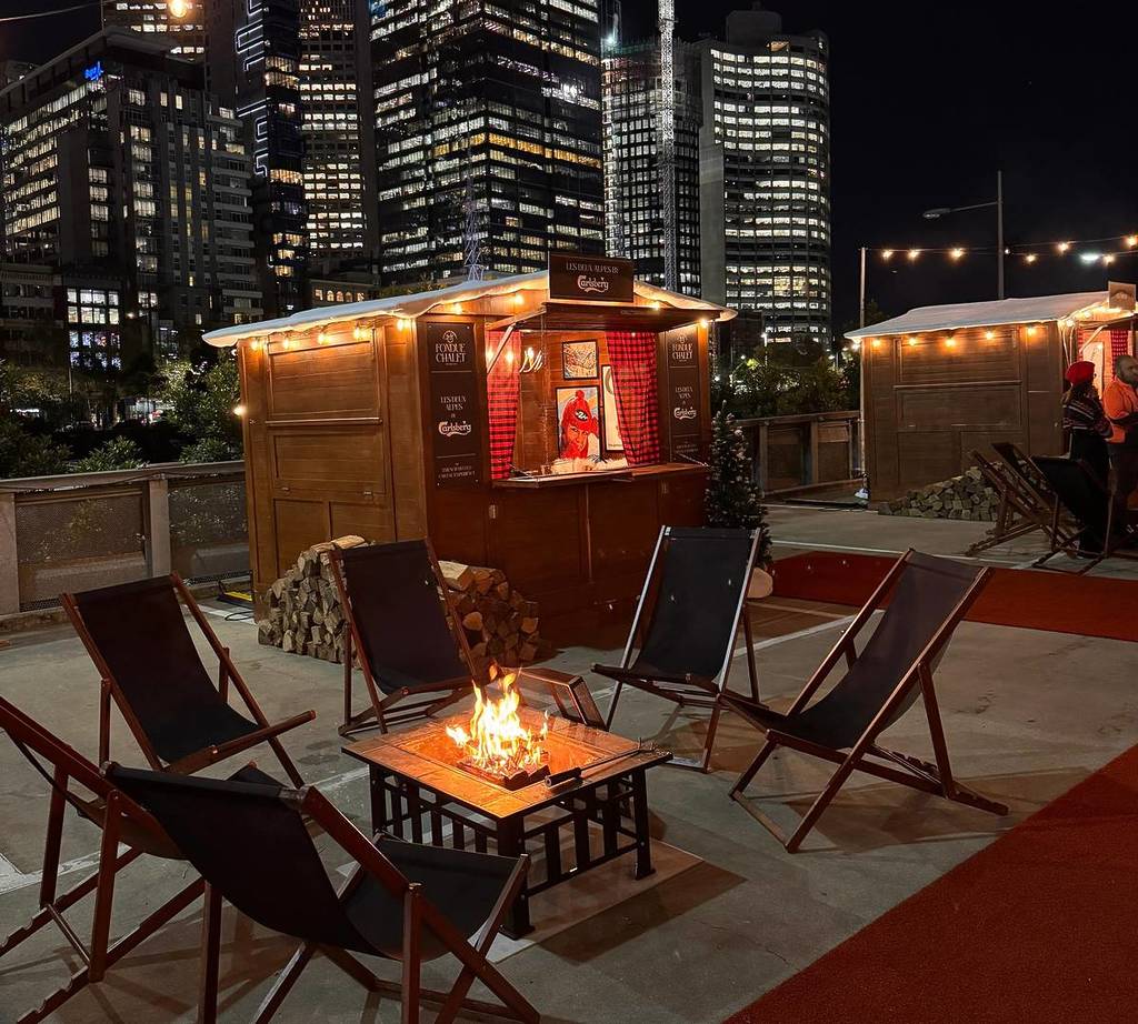 chairs around a firepit and a small chalet in the background for the Fondue Chalet experience