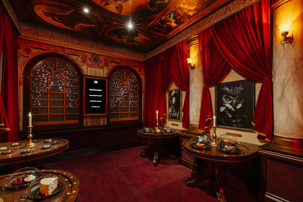 inside one of the themed rooms at Hijinx Hotel, it has paintings of animals on the wall and pretend food on fancy tables