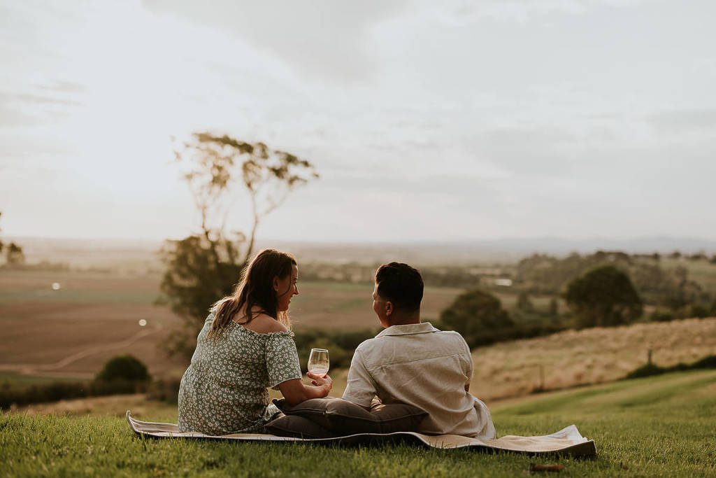 a couple drinking wine looking at hills and paddocks in Gippsland