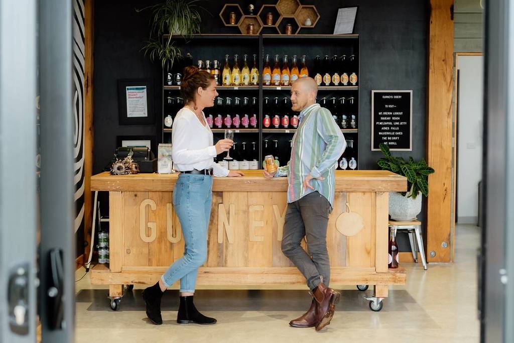 man and woman holding cider and chatting at Gurneys Cider, one of the vendors for Eat Drink Play Gippsland