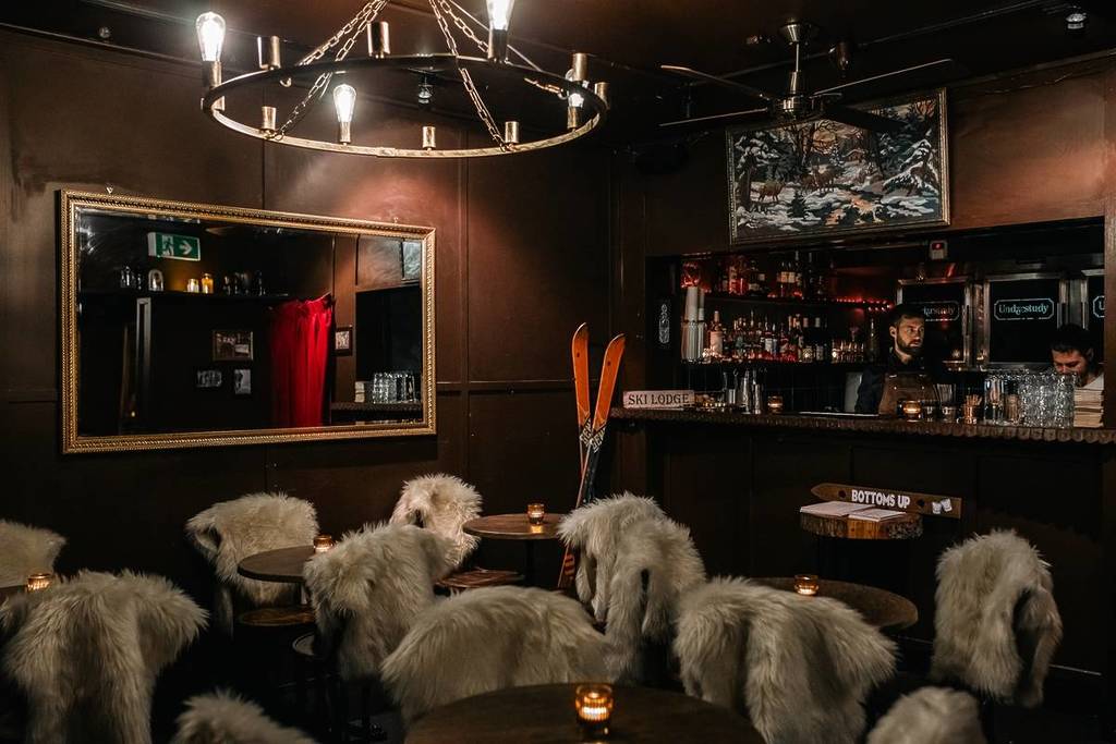 tables, chairs, bar area and ski décor in The Understudy Ski Lodge