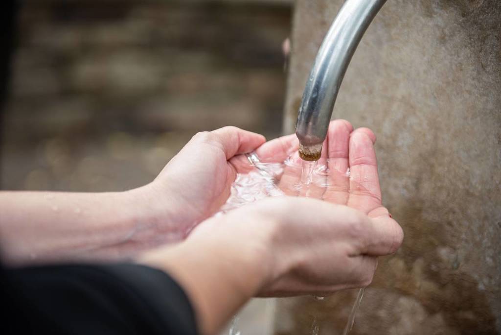 cupped hands catching the water from one of the mineral springs pumps
