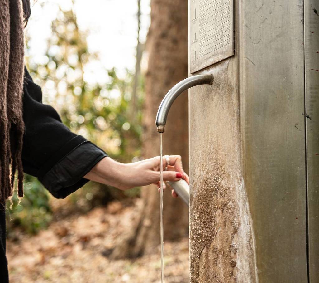 woman using a mineral springs tap or pump in Hepburn Springs