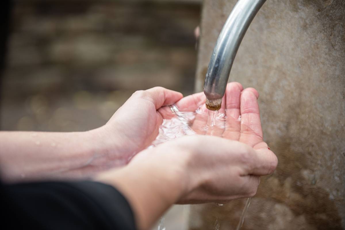 Hands cupping flowing water from the Hepburn Mineral Springs Reserve, showcasing Daylesford's famous mineral waters