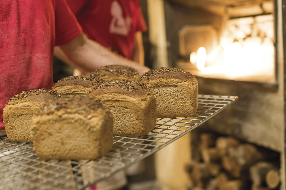 Freshly baked loaves of bread being pulled from a wood-fired oven at a bakery in Trentham, Victoria