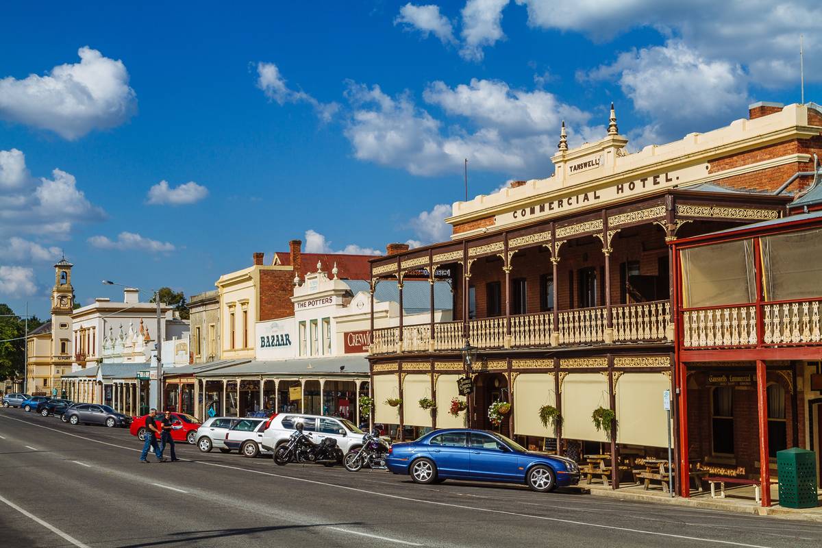 Charming historic buildings and the Tanswell's Commercial Hotel in Beechworth, Victoria, under a bright blue sky with some street activity