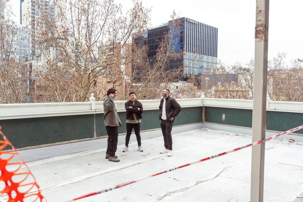 three people from MAMAS Dining Group standing in the rooftop area which is still being built