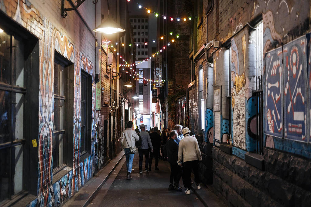 people walking down Tattersalls Lane, which has graffiti on the walls and fairy lights in the air