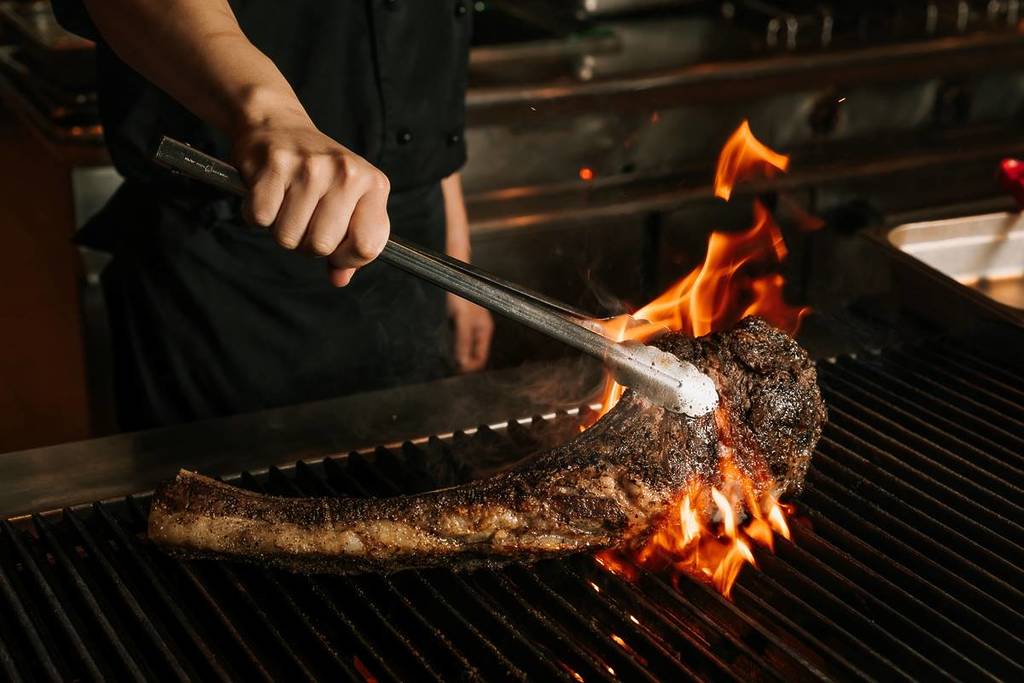 man cooking huge cut of meat over a fire