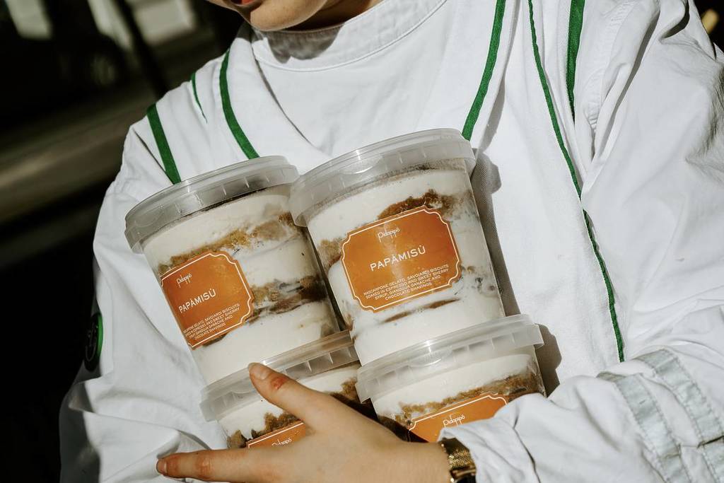 someone holding two tubs of papamisu from Pidapipo