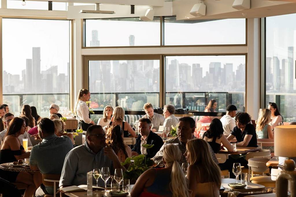 people dining inside Beverly Rooftop, with a view of the Melbourne skyline