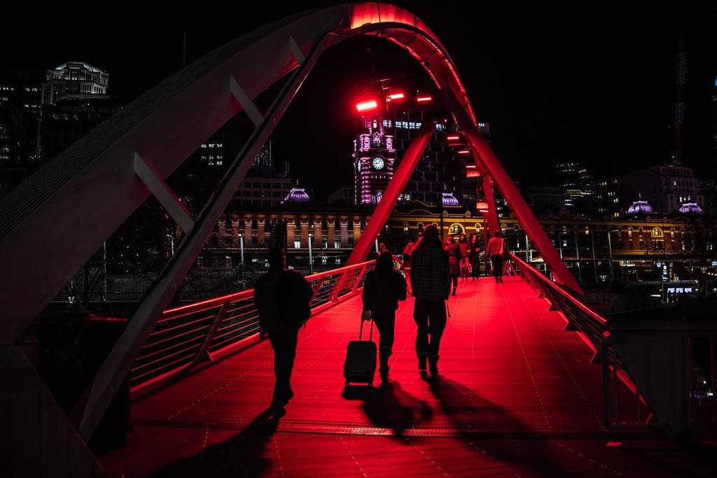 people crossing Evan Walker Bridge, lit up in red