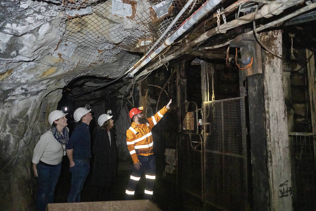 man in high vis pointing out something in the Central Deborah Goldmine in Bendigo to tourists in hard hats