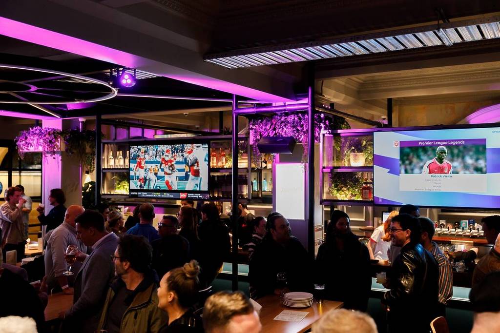 people in Harvey's Sports Bar & Grill watching an American football game