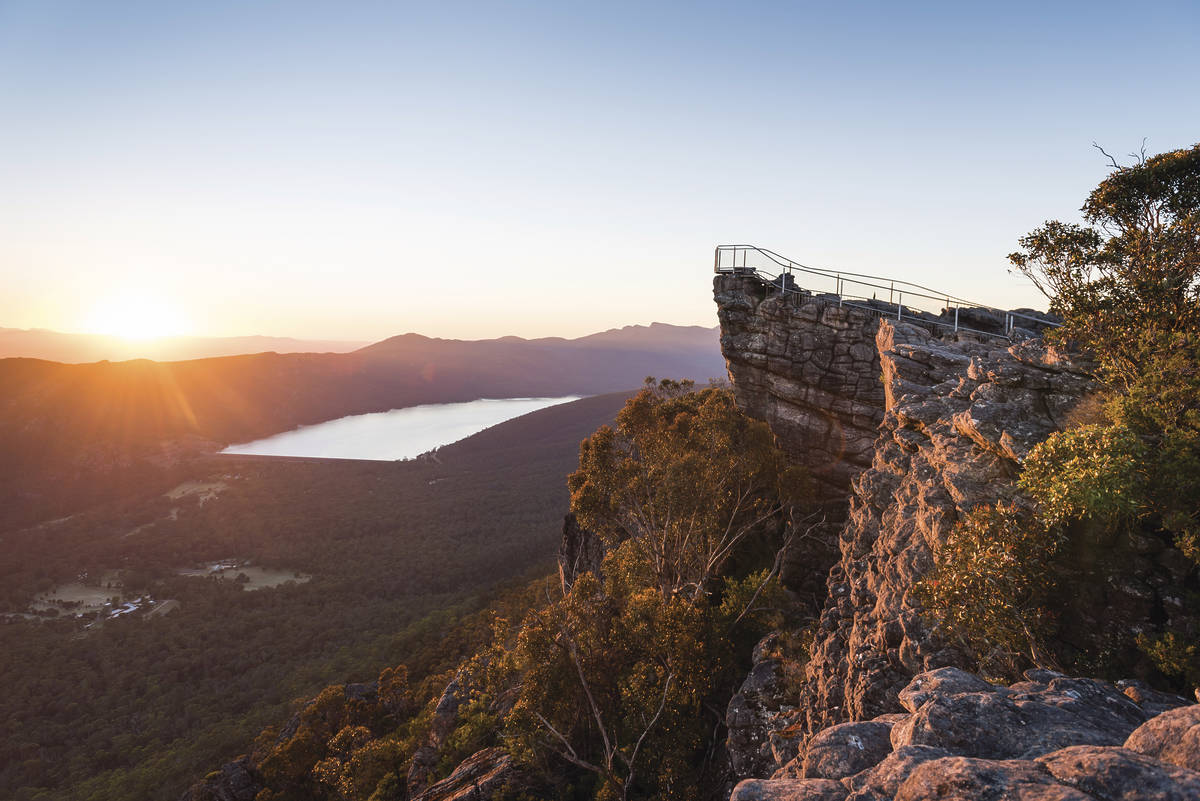 Sunset view from the Pinnacle Lookout in the Grampians, overlooking a vast valley and lake, with the rocky outcrop and viewing platform in the foreground