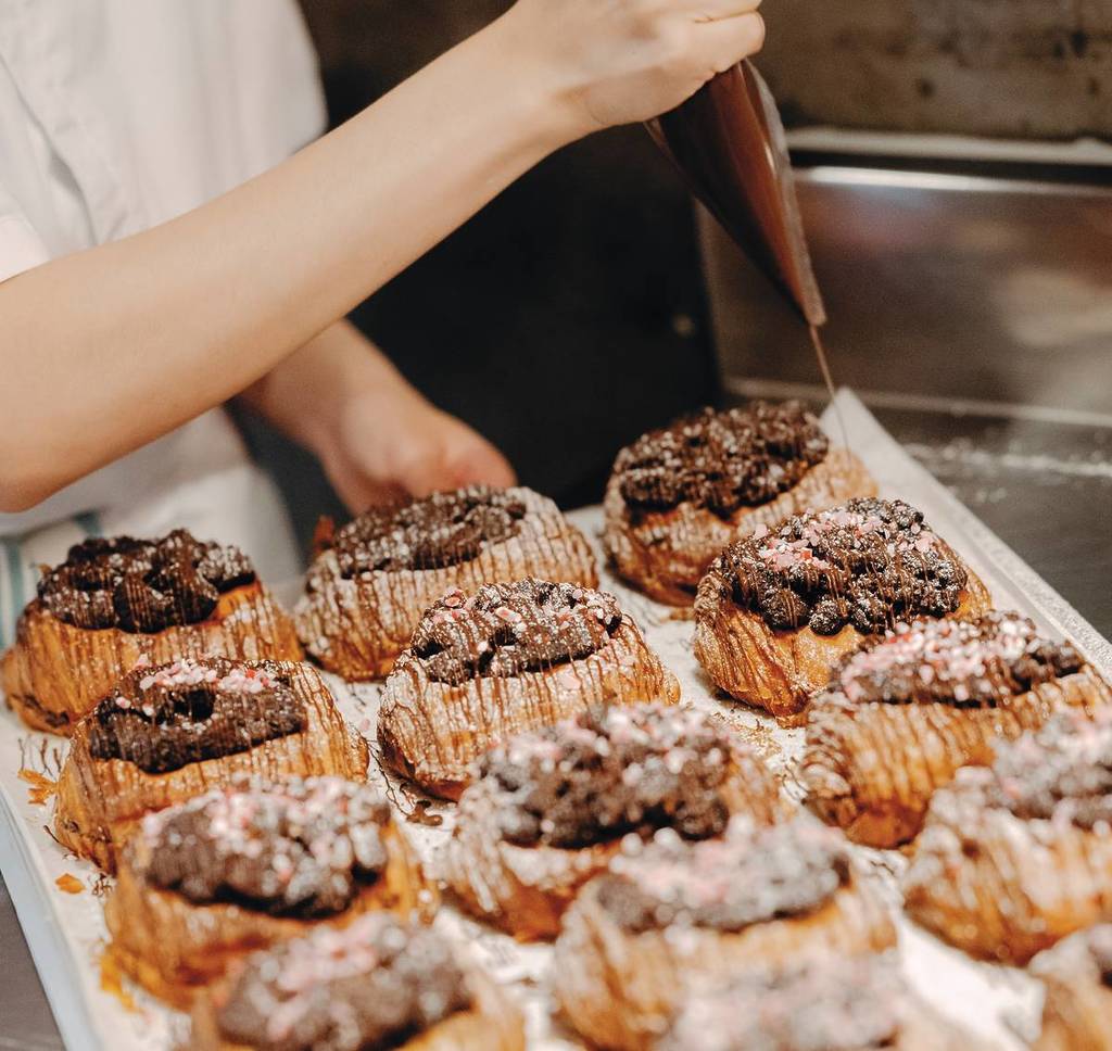person putting chocolate on pastries from Lune Croissanterie