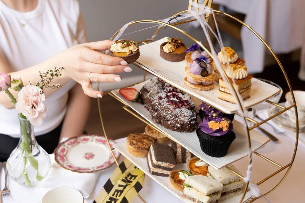 woman picking up a sweet item from the Mary Eats Cake Halloween high tea