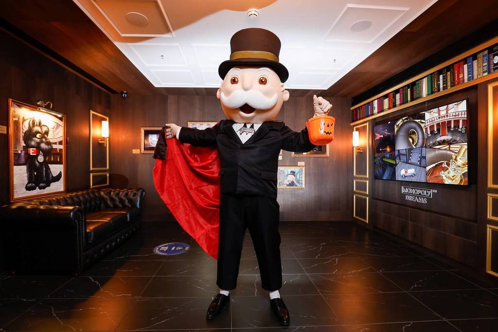 Mr Monopoly wearing a cape and holding a pumpkin pail
