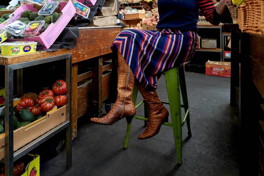 woman in brown heeled boots sitting at a food store at Prahran Market