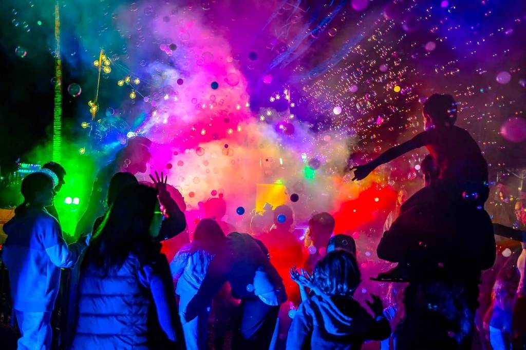 people dancing among bubbles and colourful smoke