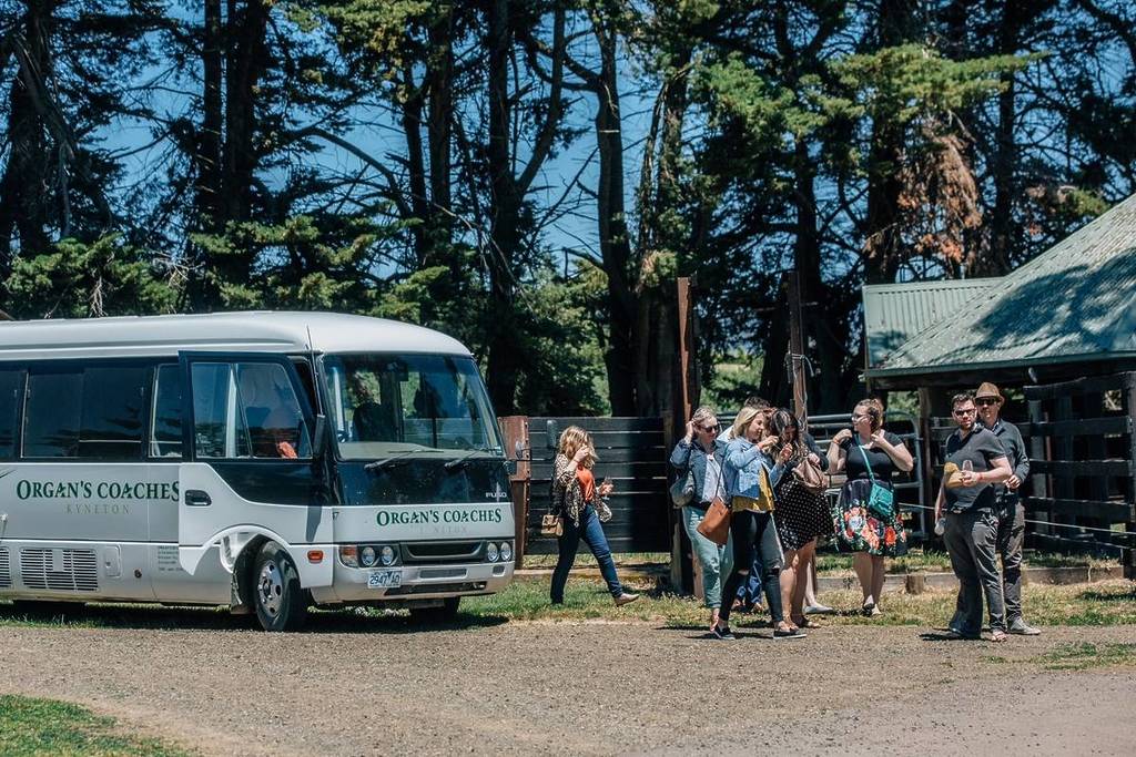 a bus dropping people off at a winery on a sunny day during Budburst Wine Festival