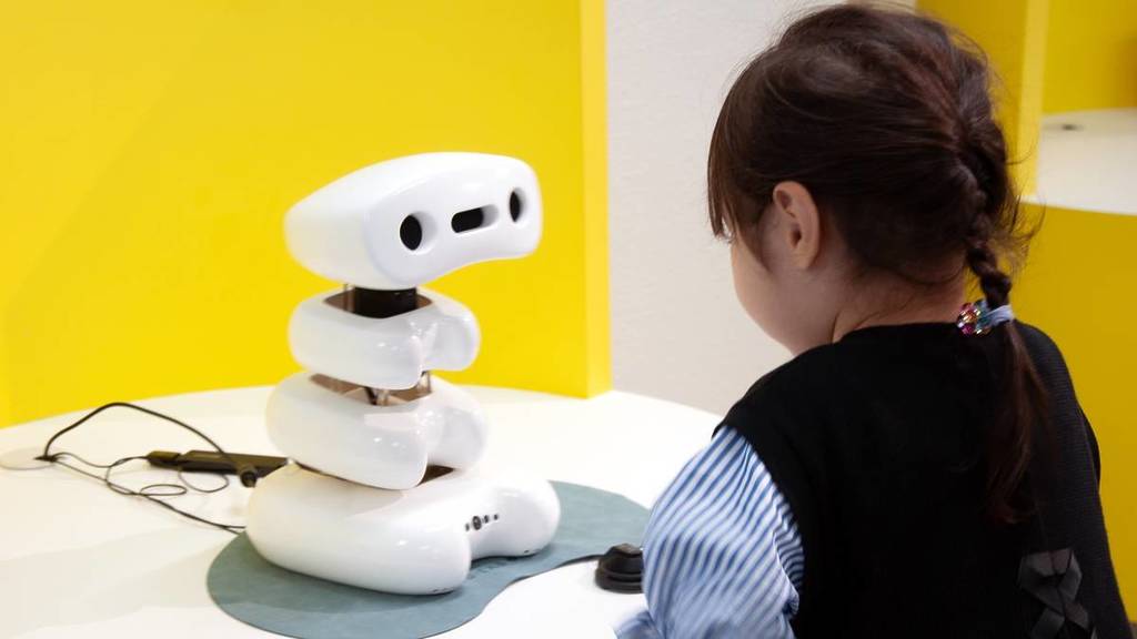 a small wobbly robot with a cute face talking to a child. This robot is Talking Bones, one of the Weak Robots