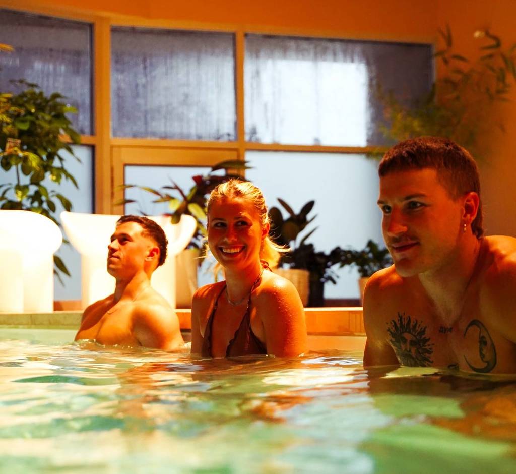 a woman and two men hanging out in the cold plunge at Wellness Social Club