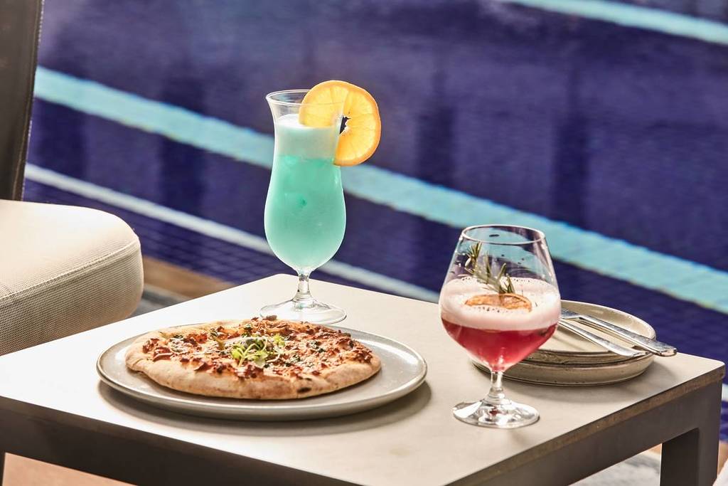 pizza and two cocktails by the pool at Vibe Hotel Docklands