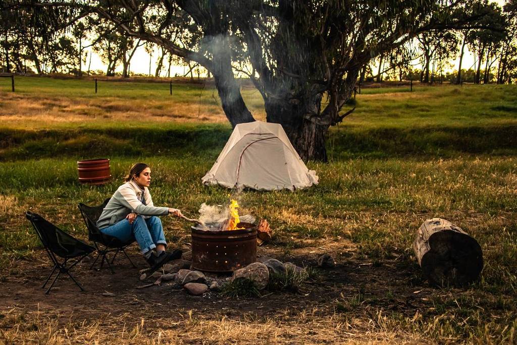 woman tending to a campfire in front of her tent at Nillawarree Farm Stay