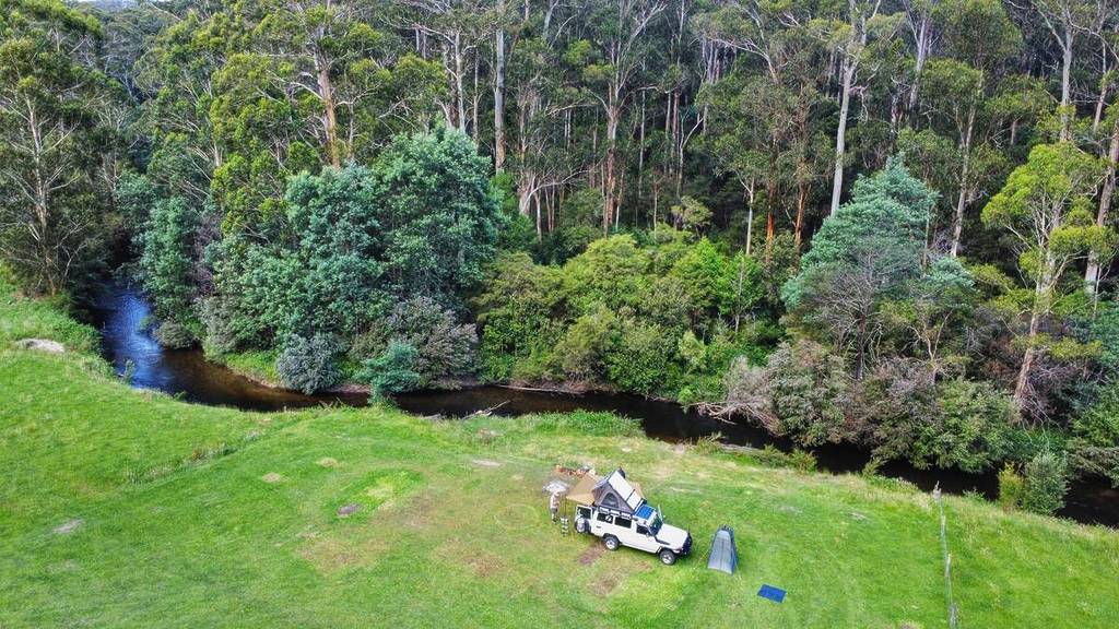 view from above of a four wheel drive and camp set up by a river at Hazelnut Valley Farmstay